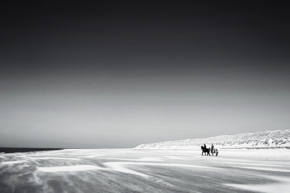 A black-and-white photo of two horse riders on the beach of Hollum on the Dutch island Ameland. 