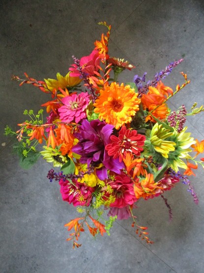 An arrangement of flowers in jewel colours. Dahlias, vrocosmia, zinnia and sunflowers.