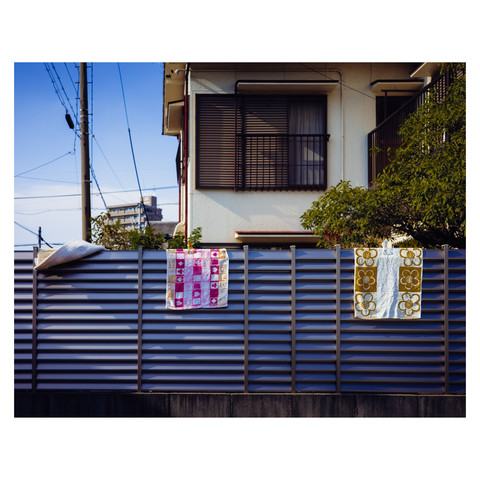 Three dishcloths are relaxing on a metal louvred fence.
