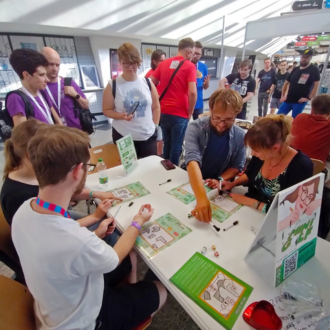People gathering around the table with Tiny Mini Golf to see the gameplay.
