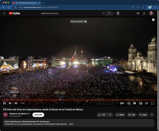 Screenshot of the video feed showing the zócalo of Mexico City completely full of people and a large stage set up in front of the cathedral with lots of lights.