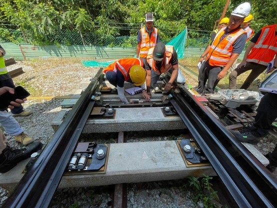 Two person measuring something on the rail track.