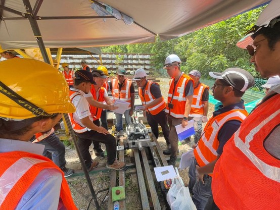 Multiple people surrounds a railway switch machine.