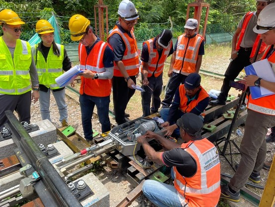 Some people are assembling track switch machine while the others are observing.