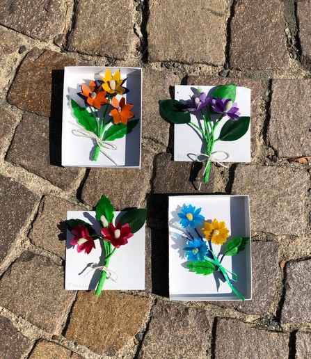 Miniatur Wachsblumensträusse in kleinen Schachteln und auf Papier liegend.