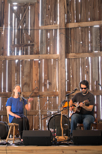 a singer and a guitarist on stage in a barn