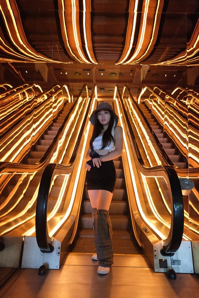 girl standing by brightly lit escalators