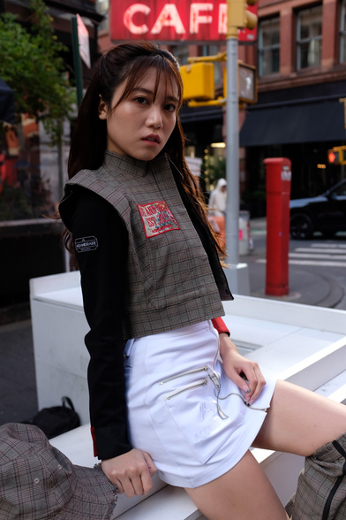 Girl in vest sitting on city street 