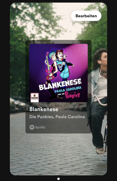 Screenshot des Spotify-Links von Paula Carolina und Die Punkies
Im Bildvordergrund ist die Werbung von Spotify für die Künstlerin und die Band.
Im Hintergrund ist eine Straße zu sehen, auf der Paula Carolina mit einem Fahrrad fährt.