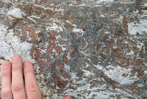 A pink hand rest on a coarsely crystalline white, pink, and blue rock surface