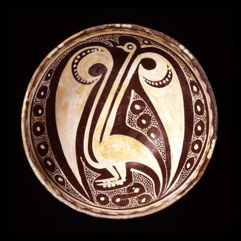 Cuenco marrón con un cisne estilizado con un cuello y alas largas. Debajo de los pies tiene una serie de 4 círculos.