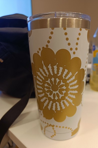 A white big thermo mug with a golden flower figure 