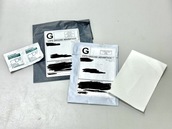 Two mail packages with personal/address info blacked out, sent as part of an Amazon brushing scam. The contents of one packages was a joined pair of moist towelette packages. The other contained a single blank Avery-style crack-and-peel address label.