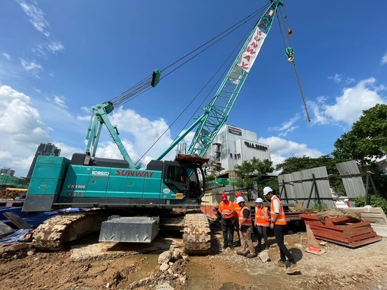 A group of people by the side of a lifting machinery.