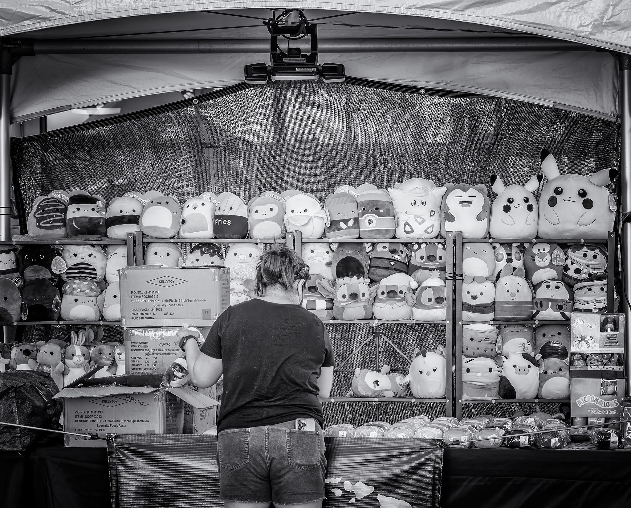 Vendor restocks plush toys in her stand at a street fair in Honolulu.