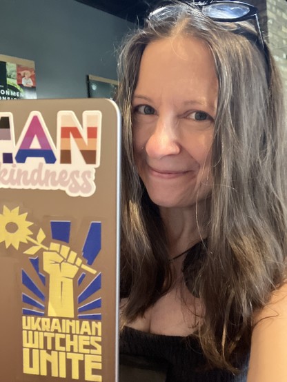 Woman sits behind a laptop with the Ukrainian Witches Unite sticker visible. 