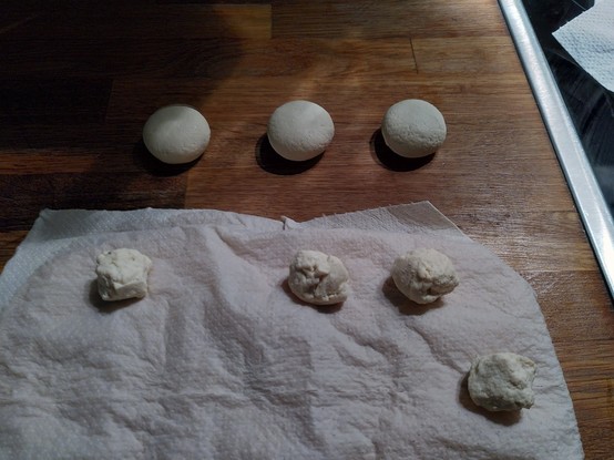 Cream cheese balls laying on a kitchen towel, with three already kneeded together small round cheeses in the back.