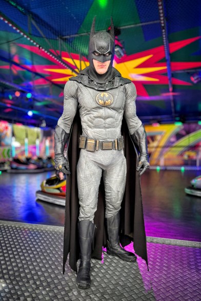 A Batman cosplayer posing in front of a dodgems/bumper cars on the Oldenburg Kramermarkt, a large funfair event in Northern Germany.