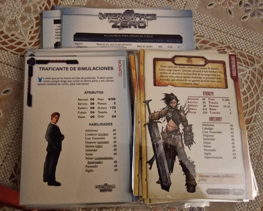 Tarjetas de ayuda y personajes pregenerados apilados de la ambientación Interface Zero. También se ve una pila de personajes pregenerados de Pathfinder Salvaje.