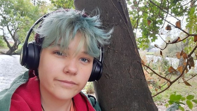 A person with blueish hair and headphones