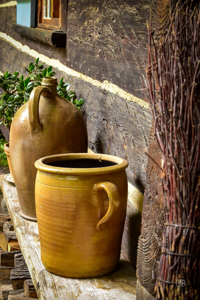 Crockery and handmade broom on hewn wooden bench outside Sorbian cottage, Lehde Open-Air Museum, Spreewald, 6 Oct 2023. Nikon D5600, Nikkor DX 35 mm ƒ1.8G, ISO 2000, ƒ7.1, 1/80s