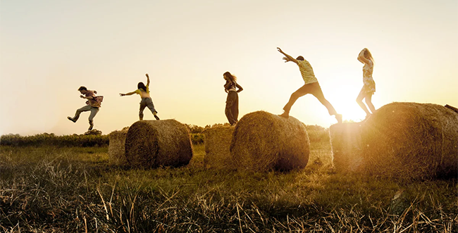 The promotional poster for Déter shows five teenagers in a field by the sunset, jumping from one bale of hay to another with joy and innocence.