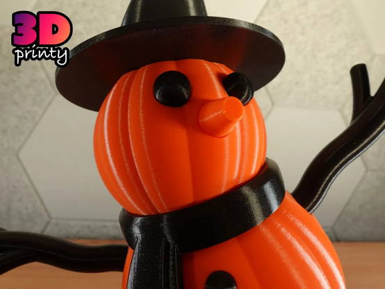 Photo of a 3D printed giant snowman with pumpkins instead of snowballs. The snowman is wearing a black scarf and witch hat.