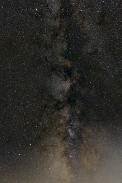A swath of the Milky Way, appearing as a column of billowing clouds of stars and nebulae, interspersed with darker lanes of dust, against a starry sky, with the glow of the horizon below. The constellations Sagittarius, Scutum, and Aquila are visible, along with the Eagle, Swan, and Lagoon nebulae, globular cluster M22, and many other features.