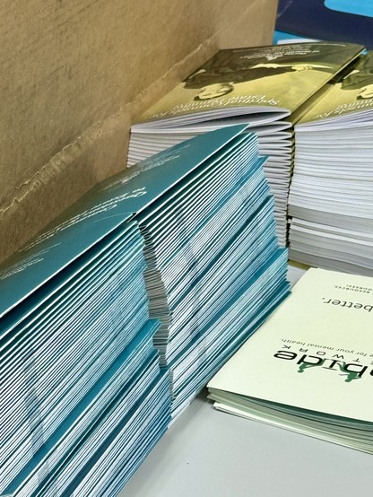 Stacks of saddle stitch booklets with full ink bleed and a square-pressed fold simulating the appearance of perfect bind finishing.