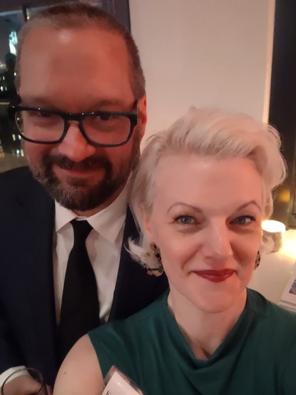 A middle-aged couple smiling into the camera because it's the first time they've been out somewhere fancy in like four years or something