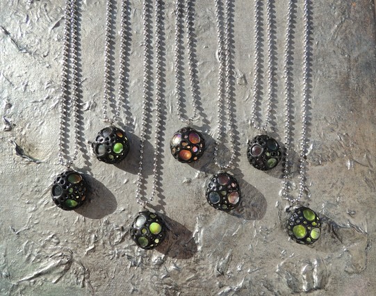 Schwarzer Schmuck aus Fimo mit Glas. Die schwarze Fimo Schicht ist löchrig und man kann das bunte Glas sehen.