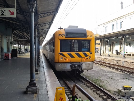 Ein Regionalzug mit gelbem Kopf im alten Bahnhof von Coimbra.