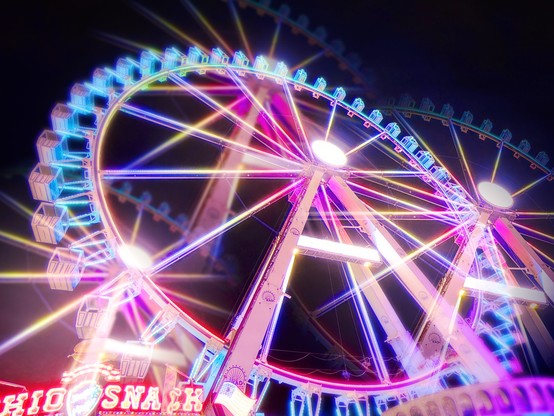 A colourful illuminated ferris wheel on a fair in the evening, edited with multiple exposure effect. 