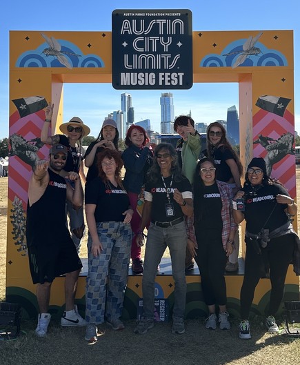 Team of 10 Headcount volunteers enjoying life in front of an ACL Fest photo op frame with the Austin skyline in the background