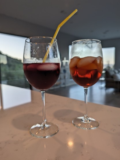 Two wine glasses with mixed drinks sitting on a counter.