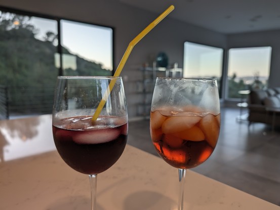 Two wine glasses with mixed drinks sitting on a counter.