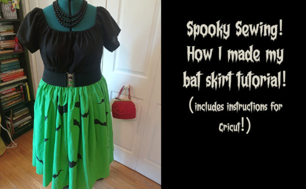 Dress form wearing a black top in the green skirt with bats on it.