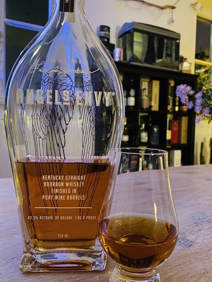 Talk dropshaped bottle  of Bourbon. Silhouette sog Angels Wings shine through from the backside