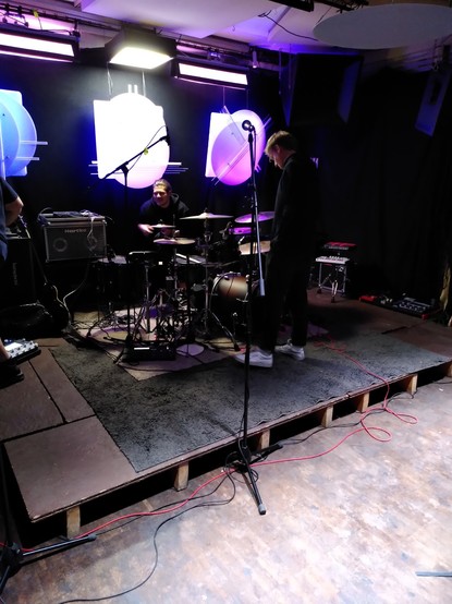 Stage of club Kulturlounge with a full drum kit and two people being on it (the stage, not the drum kit)