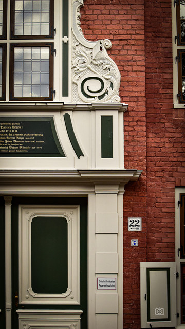 Ornate Baroque door frame with inscription in Fraktur on a red brick townhouse, Dutch Quarter, Potsdam, 16 Oct 2023. Nikon D5600, Nikkor DX 35 mm ƒ1.8G, ISO 640, -0.3 ev, ƒ10, 1/250s