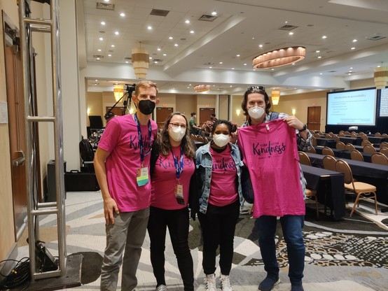 Four people wearing pink shirts that say " code with Kindness" 