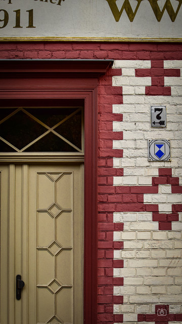Doorway with mullioned window and brick wall painted in a red and white pattern, Dutch Quarter, Potsdam, 16 Oct 2023. Nikon D5600, Nikkor DX 35 mm ƒ1.8G, ISO 640, -0.7 ev, ƒ9, 1/250s