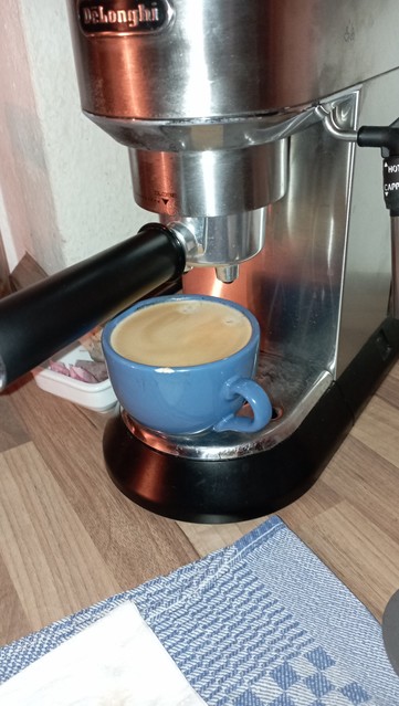 Eine gerade gebrühte Tasse Kaffee unter Kaffeemaschine, etwa 2 mm unter Oberkante 