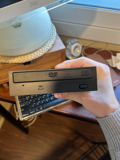 Photo showing the front of the "new" DVD drive with its front bezel still attached. This bezel needs to be removed in order for it to fit inside the iMac.