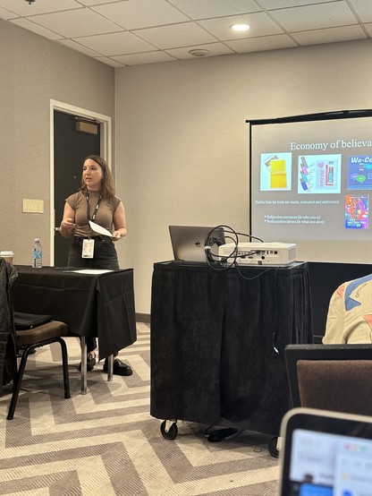 Kat Higgins standing at the front of a conference room speaking