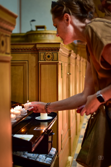 My wife lighting a votive candle at Church of the Redeemer, Sacrow, Brandenburg, Germany, 20 Aug 2023. Nikon D5600, Nikkor DX 35 mm ƒ1.8G, ISO 640, ƒ1.8, 1/200s
