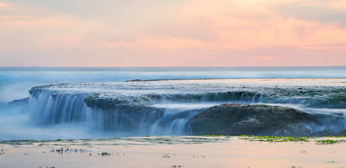 Long exposure of mini waterfall falling off exposed reef rock platform in Mornington Peninsula Melbourne Naarm 