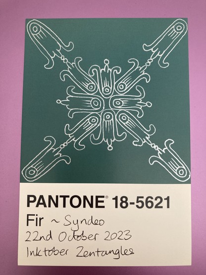 Silver inked pattern on a dark green background, looking like trumpet-shaped flowers in a group of 8 in the middle with 4 pointing in diagonally from the corners
