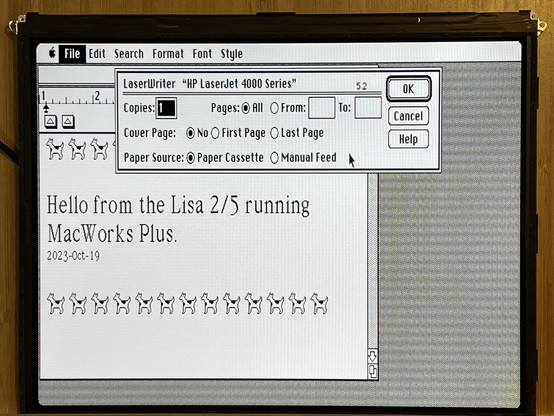 Screenshot of MacWrite showing a document that says “Hello from the Lisa 2/5 running MacWorks Plus” along with many cowdogs at the top and bottom of the page (moof!). A print dialog box is open on top for the LaserWriter driver. 