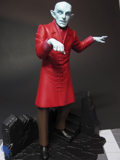 Scale model of Count Orlok from Nosferatu. Red coat, dark brown pants, pale blue skin, hands and black shoes. On a black primed base.